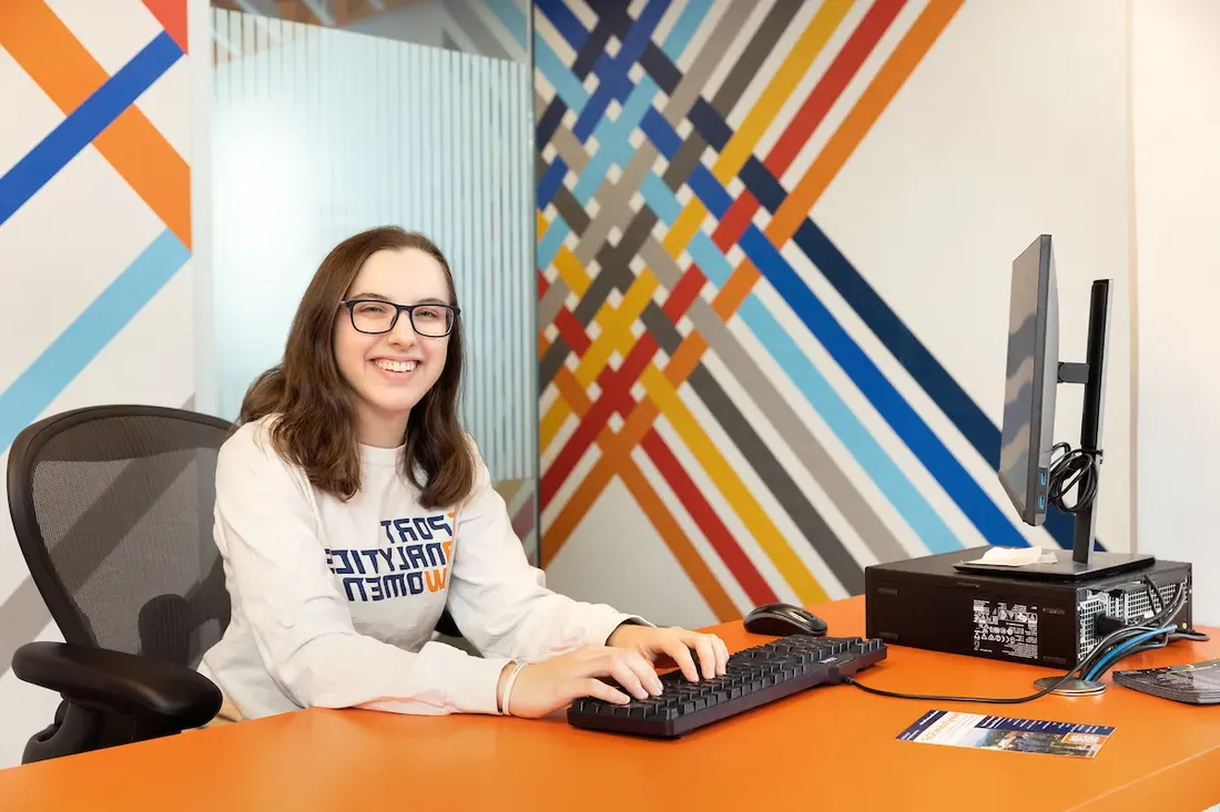 Student worker on computer at a front desk.